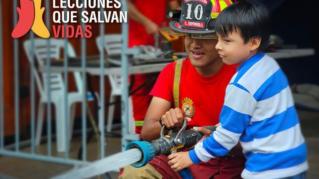 Bombero enseñando funcionamiento de una manguera a un niño