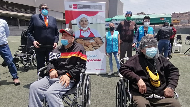 Imagen de la ceremonia de entrega de sillas de ruedas donde aparecen los representantes del CONADIS, voluntarios de Corazones Unidos y beneficiarios de Villa María del Triunfo.