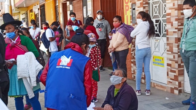 Comisionada de Defensoría del Pueblo conversando con persona adulta mayor en una calle transitada. 