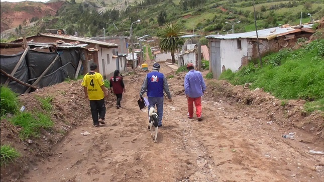 Comisionado de la Defensoría del Pueblo junto a dos personas caminando por una carretera destruida.