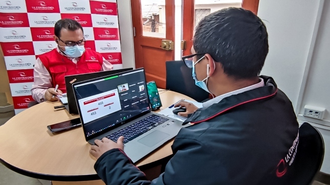 Imagen JPG de dos colaborador de la Contraloría en los interiores de una oficina, sentado y participando de una video conferencia de los resultados de servicios de control Amazonas 2020.