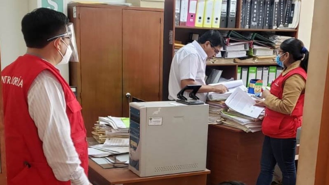 Imagen JPG de tres colaboradores de la Contraloría revisando documentos en el interior de UGEL Casma.