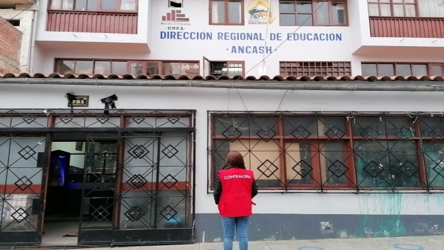 Imagen JPG de colaboradora de la Contraloría mirando la fachada de la Dirección Regional de Educación de Áncash.