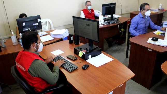 Imagen JPg de varios colaboradores de la Contraloría sentados en una silla y trabajando desde sus laptops en los interiores de una oficina.