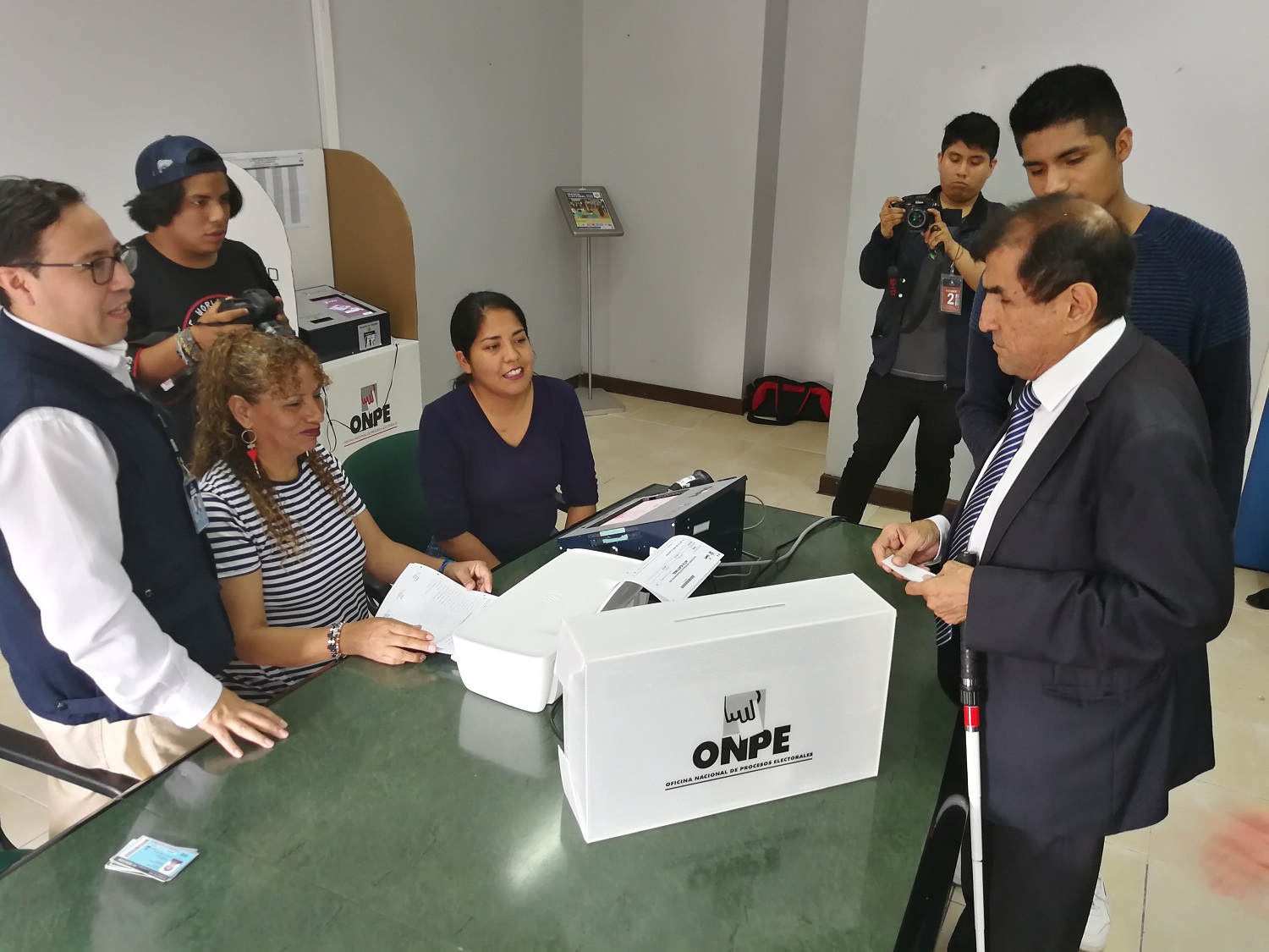 En la foto 6 personas que están en una mesa de votación para ejercer su derecho al sufragio.