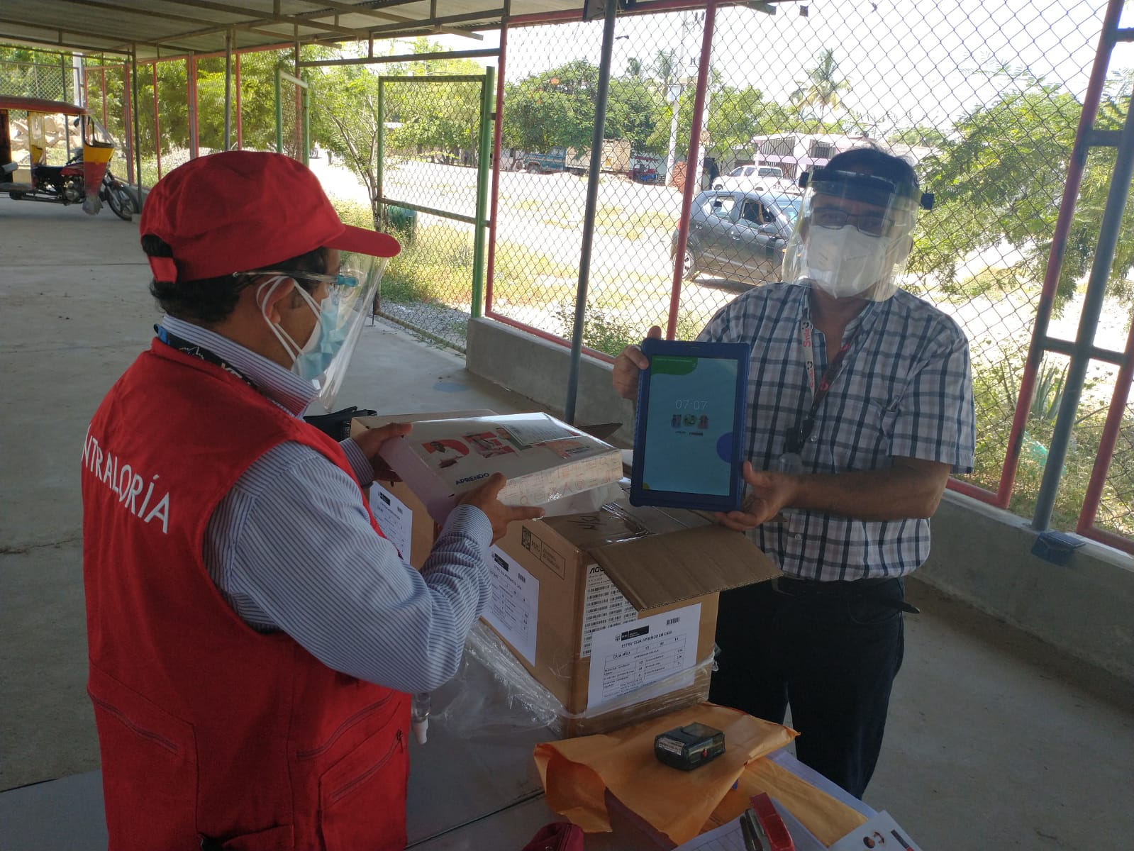 Imagen JPG de colaboradores de la Contraloría supervisando entrega de tablets a escolares y docentes en Piura.