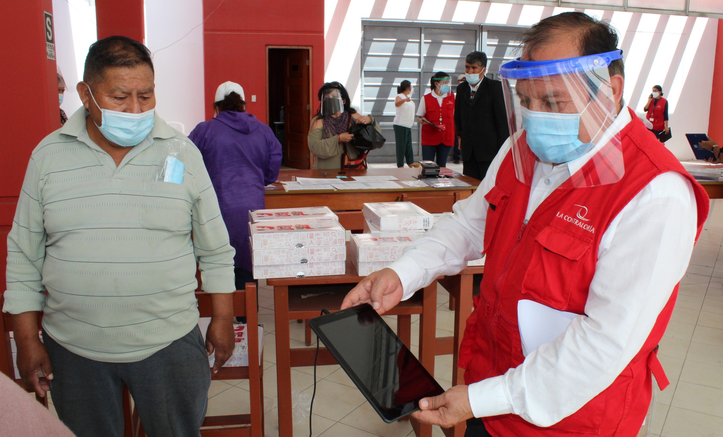 Imagen JPG de colaborador de la Contraloría supervisando entrega de tablets a escolares y docentes en Tacna.