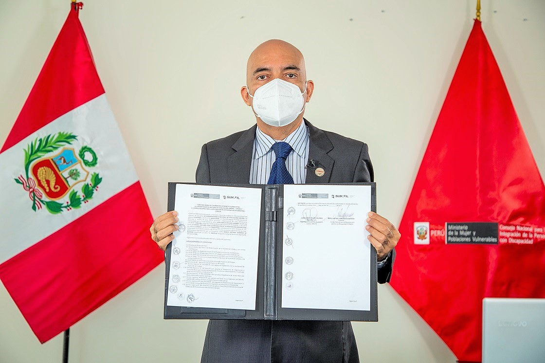 En la foto el presidente del Conadis Marco Antonio Gamarra La Barrera esta parado y muestra el convenio firmado