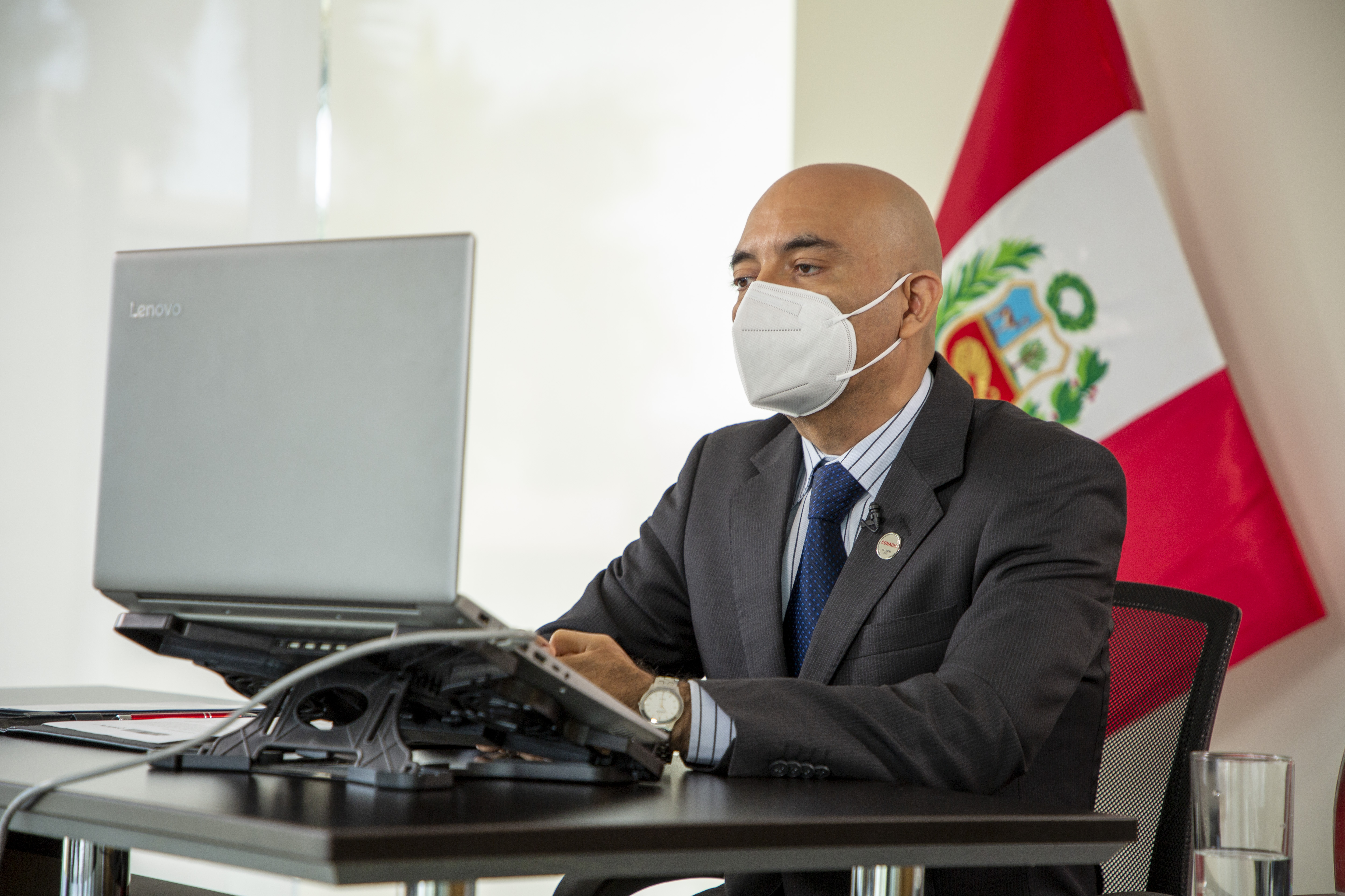 En la foto el presidente del Conadis Marco Antonio Gamarra La Barrera esta sentado frente a su laptop atento a la ceremonia virtual que se viene realizando.