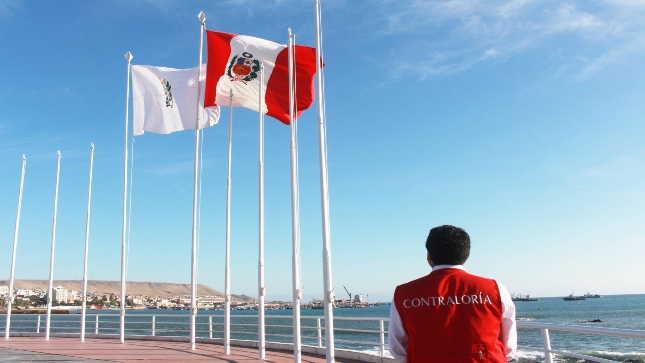 Imagen JPG de colaborador de la Contraloría contemplando la bandera del Perú con el fondo del mar en Moquegua.
