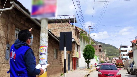 Foto de comisionado de la Defensoría del Pueblo frente a un poste con propaganda electoral