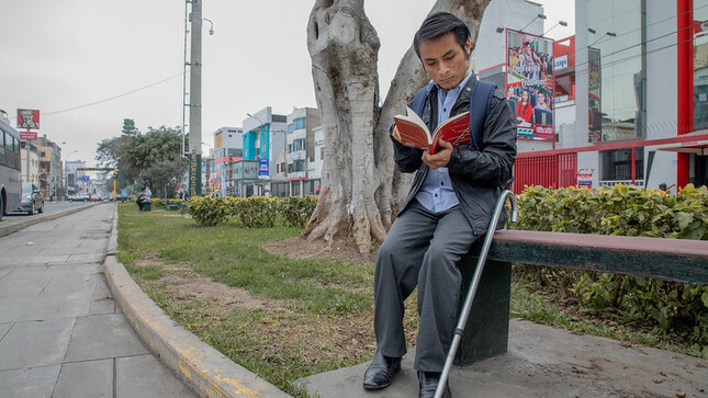 Persona con discapacidad leyendo en una calle.