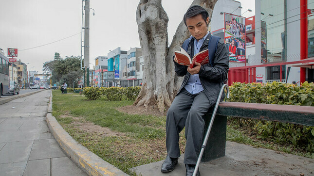 Persona con discapacidad leyendo en una calle.
