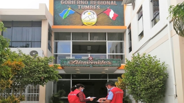Imagen JPG de dos colaboradores de la Contraloría parados en la puerta de ingreso del Gobierno Regional de Tumbes.