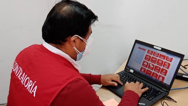 Imagen JPG de colaborador de la Contraloría sentado revisando información en su laptop.