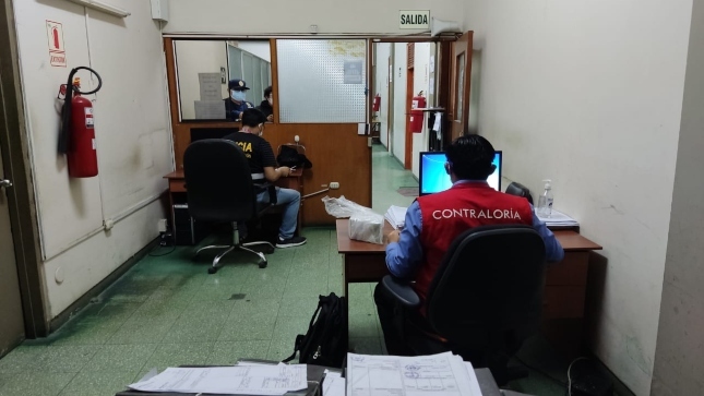 Imagen JPG de colaborador de la Contraloría y de la Policía sentados en una oficina buscando información en computadoras sobre intervención de oficinas del Gobierno Regional de Piura.