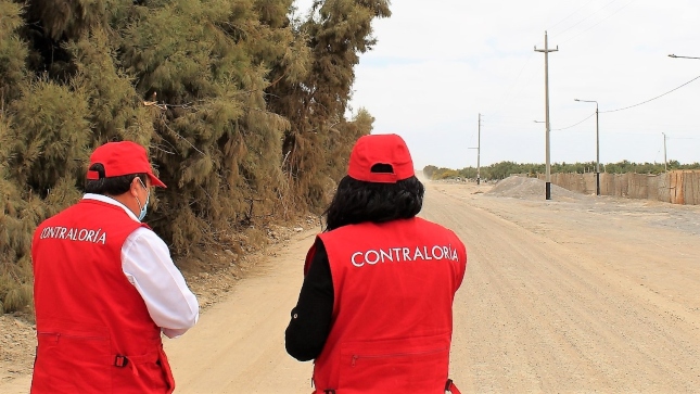 Imagen JPG de dos colaboradores de la Contraloría supervisando mantenimiento vial en Tacna.