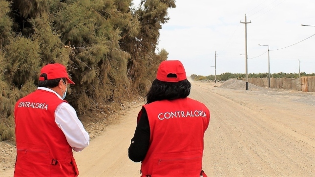 Imagen JPG de dos colaboradores de la Contraloría supervisando mantenimiento vial en Tacna.