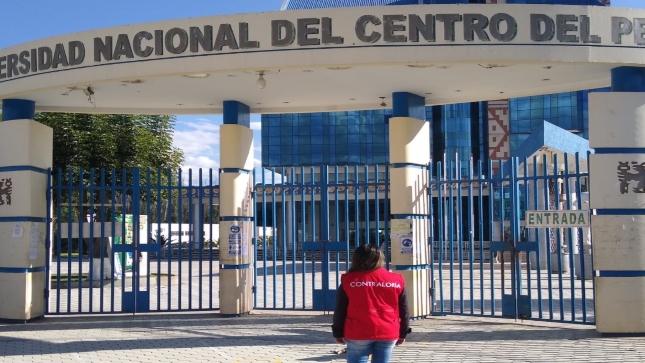 Imagen JPG de colaboradora de la Contraloría mirando la puerta principal de la Universidad Nacional del Centro en Junín.