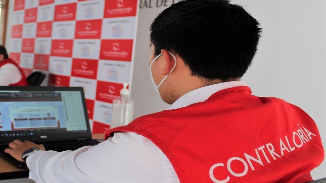 Imagen JPG de colaborador de la Contraloría sentado revisando información sobre curso virtual en provincia Tambopata.