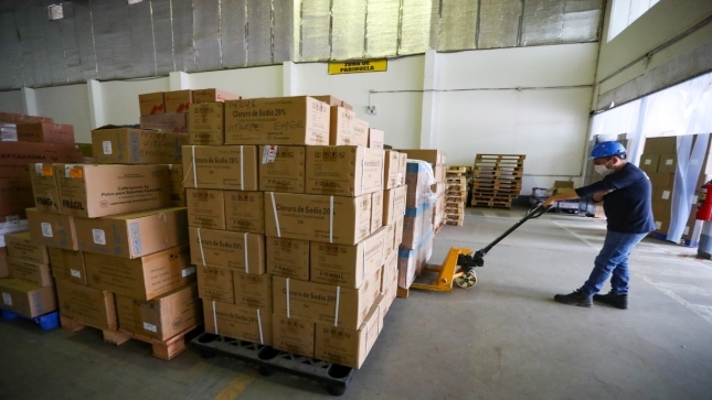Imagen JPG de un trabajador de fábrica manipulando el traslado de productos farmacéuticos apilado en varias cajas.