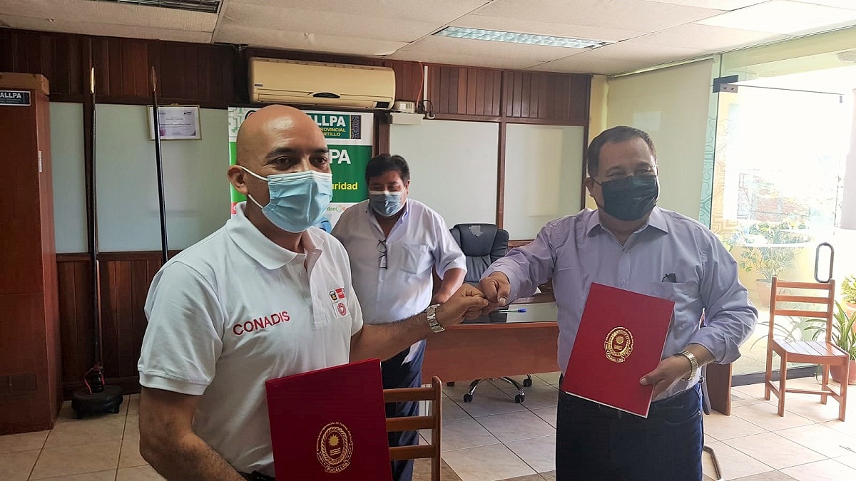 El presidente del Conadis, Marco Antonio Gamarra La Barrera y el alcalde de la provincia de Coronel Portillo, Segundo Pérez Collazos muestran convenio en un cartapacio rojo.