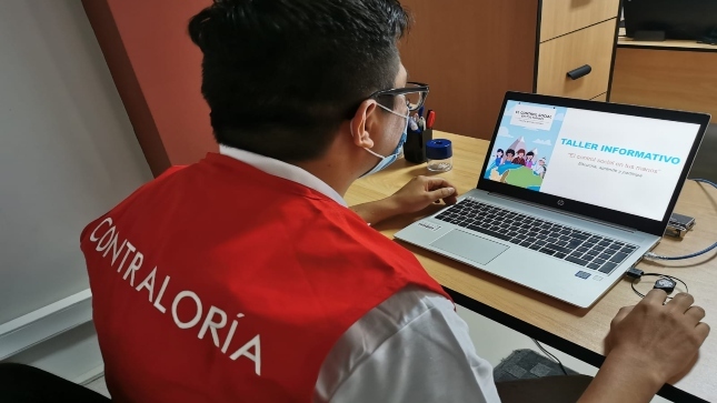 Imagen JPG de colaborador de la Contraloría sentado en su escritorio, revisando información en su laptop sobre curso virtual “El control social en tus manos” Ayacucho.