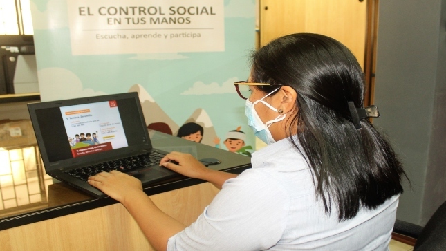 Imagen JPG de colaboradora de la Contraloría sentada, mirando información sobre el  curso virtual “El control social en tus manos” Tumbes en su laptop.