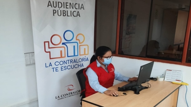 Imagen JPG de colaboradora de la Contraloría sentada en su escritorio con su computadora participando de la Audiencia Pública Virtual “La Contraloría te escucha” en Huánuco.