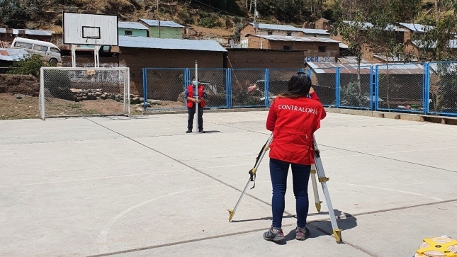 Imagen JPG de dos colaboradores de la Contraloría supervisando losa multideportiva en Pasco.