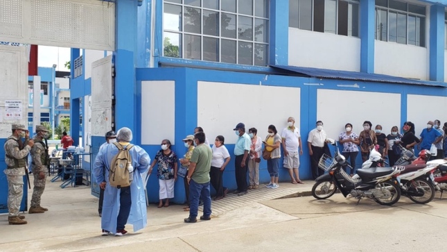 Foto de personas haciendo fila en ingreso de local de vacunacion 