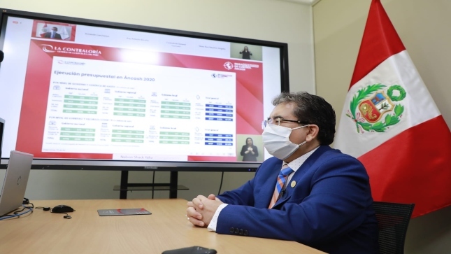 Imagen del Contralor General sentado en su escritorio con un televisor grande proyectando información en el marco del Mega Operativo de Control en Áncash.