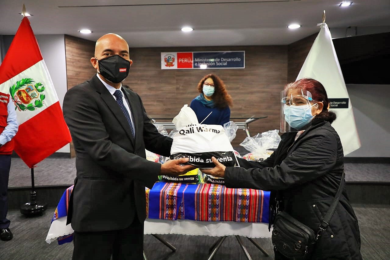 Presidente del Conadis, Marco Antonio Gamarra entrega una bolsa de víveres a una mujer representante de personas con discapacidad.