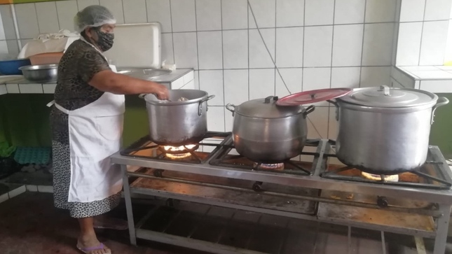 Foto de mujer preparando comida en cocina de comedor popular