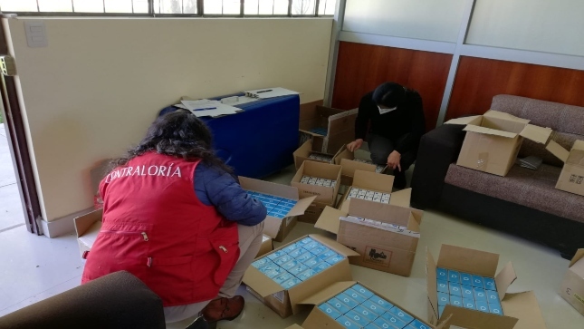 Imagen JPG de personal de la Contraloría junto a otra persona revisando varias cajas en Cajamarca.