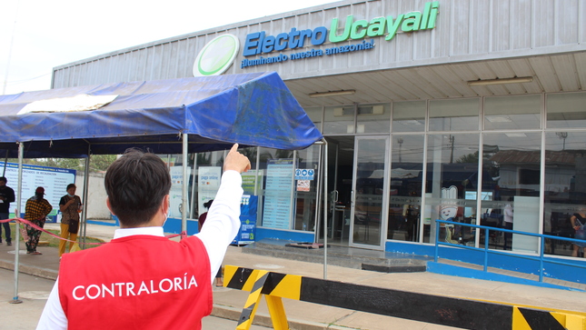 Imagen JPG del colaborador de la Contraloría señalando la fachada de la  Empresa Concesionaria de Electricidad de Ucayali S.A.