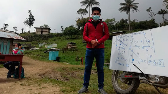 Neyber Terrones Díaz junto a la moto y la pizarra blanca posa para la cámara