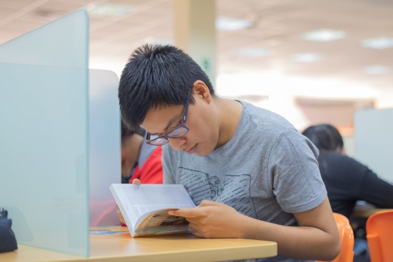 Estudiando leyendo un libro en una biblioteca