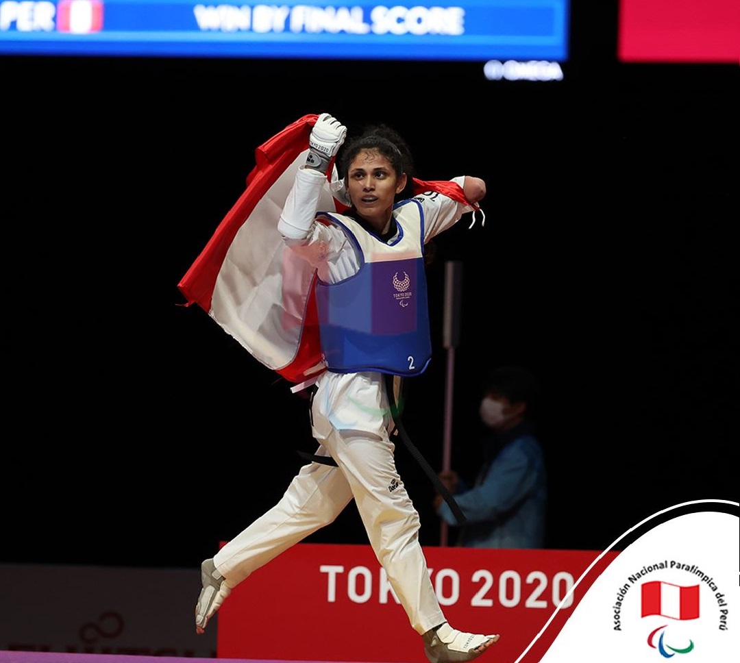 Angélica Espinoza gana la medalla de oro en los Juegos Paralímpicos de Tokio 2020 se muestra con la bandera del Perú y camina por el podio hacia la derecha.