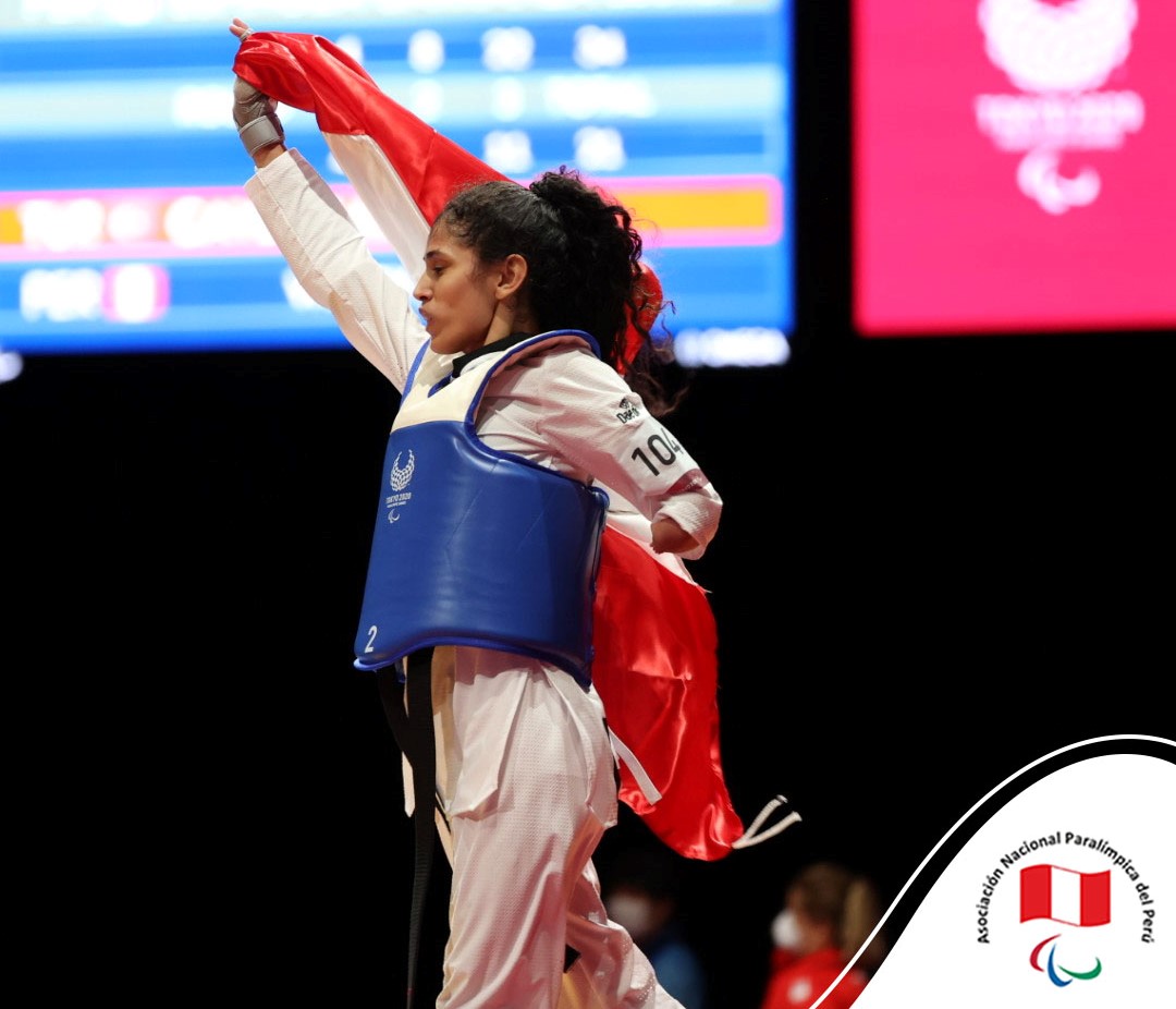 Angélica Espinoza gana la medalla de oro en los Juegos Paralímpicos de Tokio 2020 se muestra con la bandera del Perú y camina por el podio hacia la izquierda.