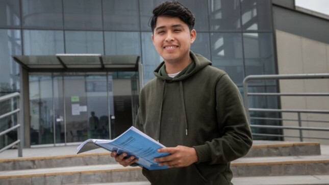 Joven afuera de una biblioteca leyendo un libro