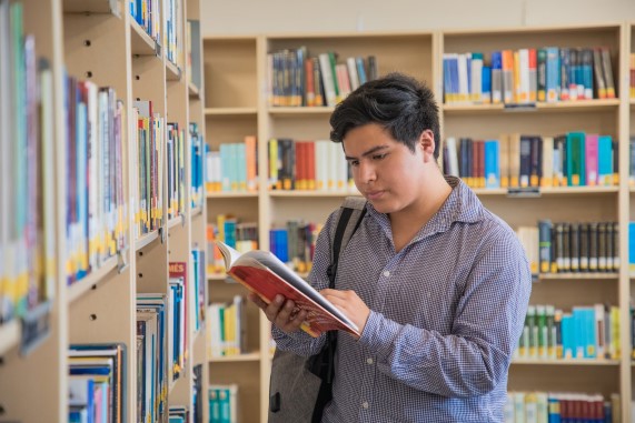 Estudiante leyendo un libro en un biblioteca