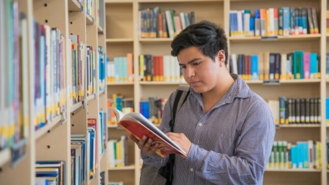 Estudiante leyendo un libro en un biblioteca
