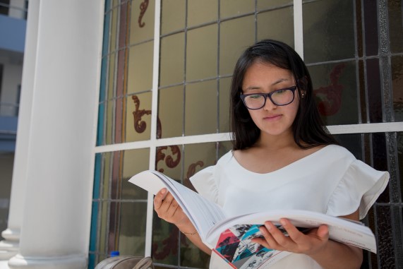 Estudiante parada leyendo un libro