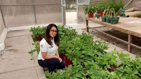 Shirley mira a la cámara sentada dentro de un invernadero