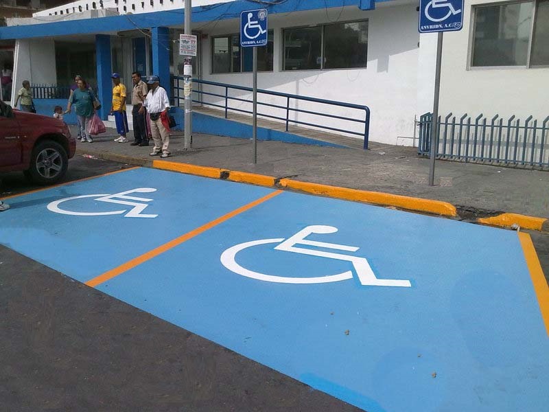 Imágenes de la señalización de estacionamiento reservado para personas con discapacidad. Fondo de color azul con la señalética de una silla de ruedas y un cartel que dice para personas con discapacidad con la grafica de la sillas de ruedas .