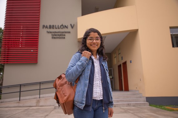 Estudiante parada en el frontis de su universidad