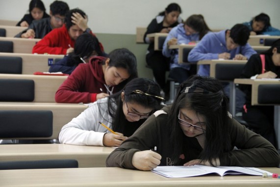 Estudiantes rindiendo su examen un salón de clase.