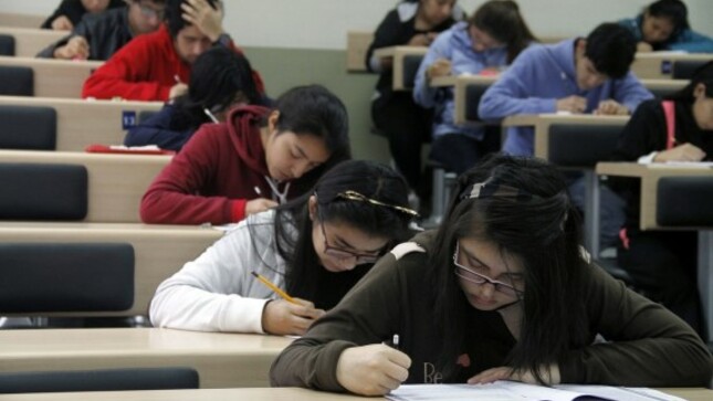 Estudiantes rindiendo su examen un salón de clase.