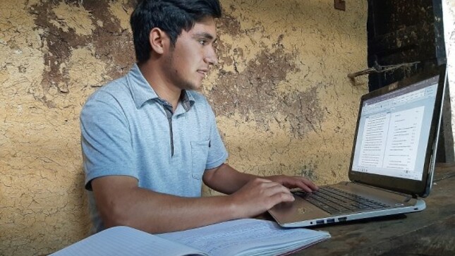 Joven estudiante haciendo su tarea frente a una computadora